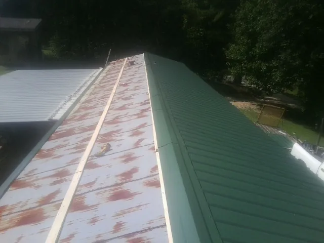 Old rusted panels beside newly installed green metal roofing — Wind Damage Roof Repair by Roofing Brothers in Forest