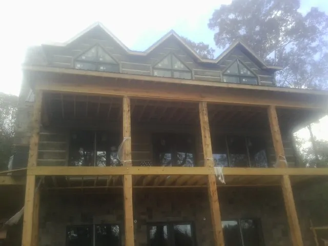 Dormers and porch framing on a large log home under construction — Roof Coating work by our crew in Forest