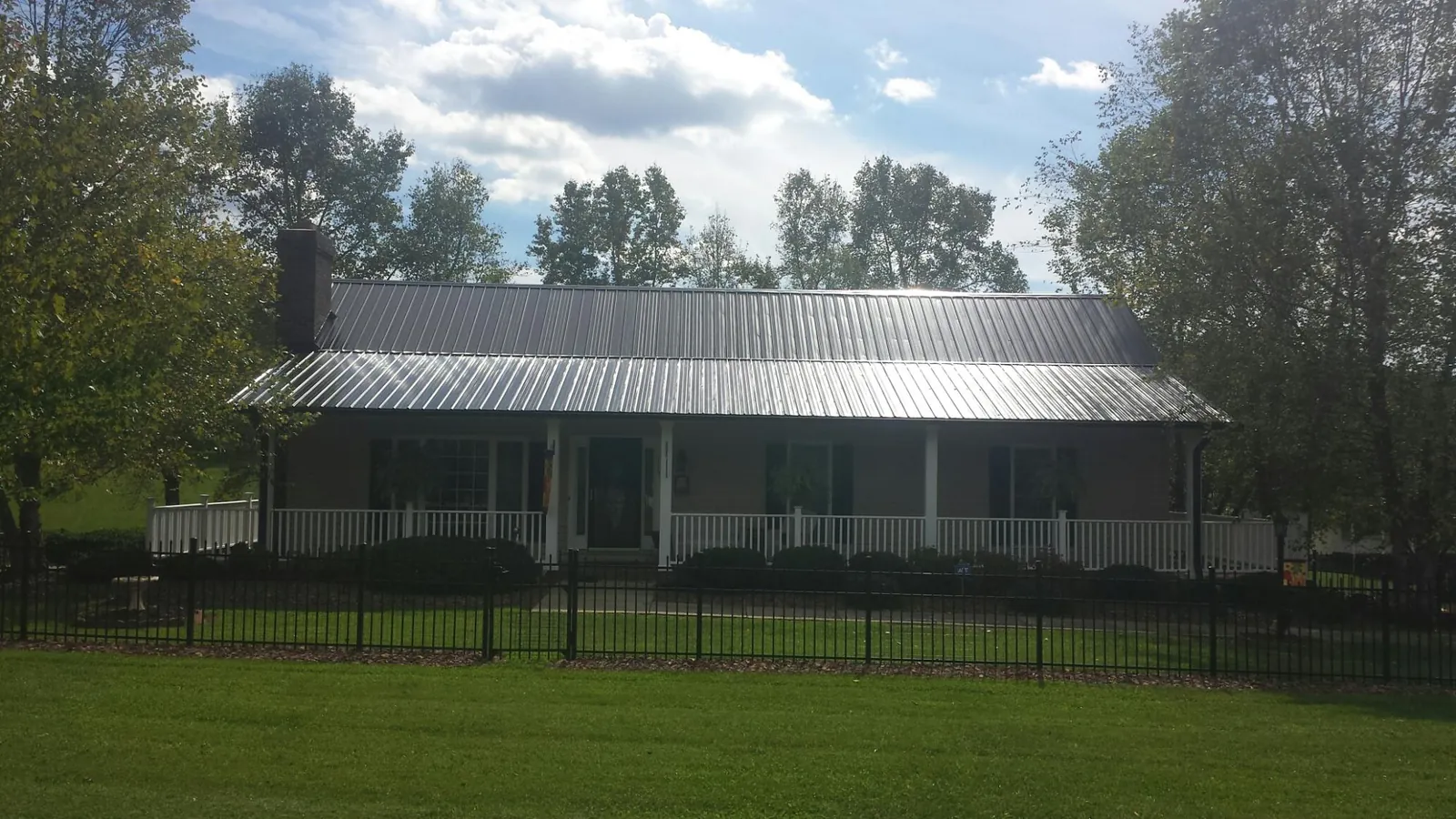 Gray metal roof on a brick ranch with a full width front porch — Gutter Guard Installation work by our crew in Forest